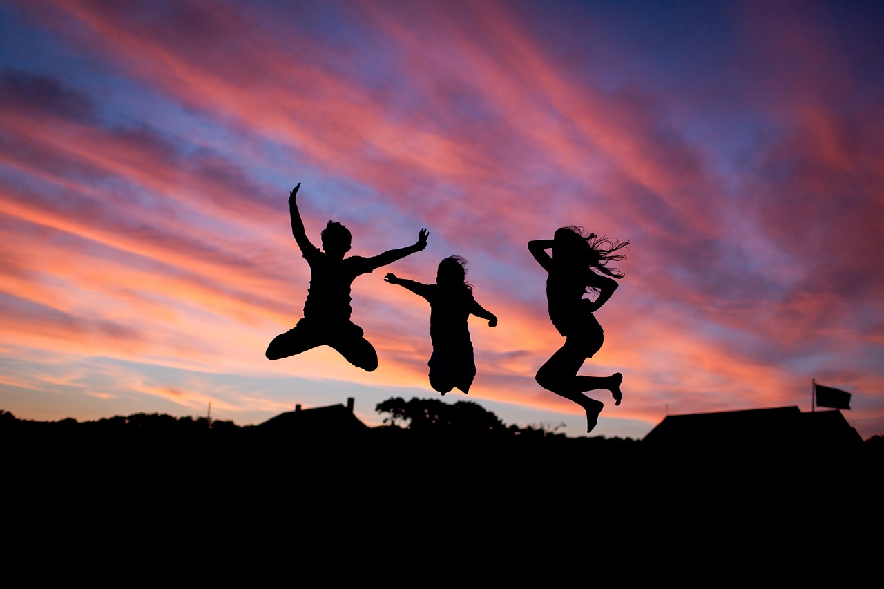 Drei Menschen die im Sonnenuntergang in die Luft springen