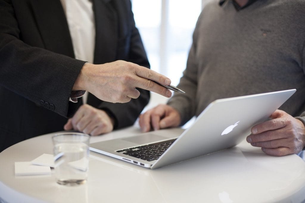 Zwei Personen stehen vor einem Tisch mit einem Laptop
