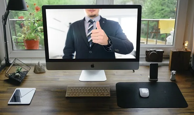 Mann im Bildschirm von Apple-Computer, hält den Daumen hoch.