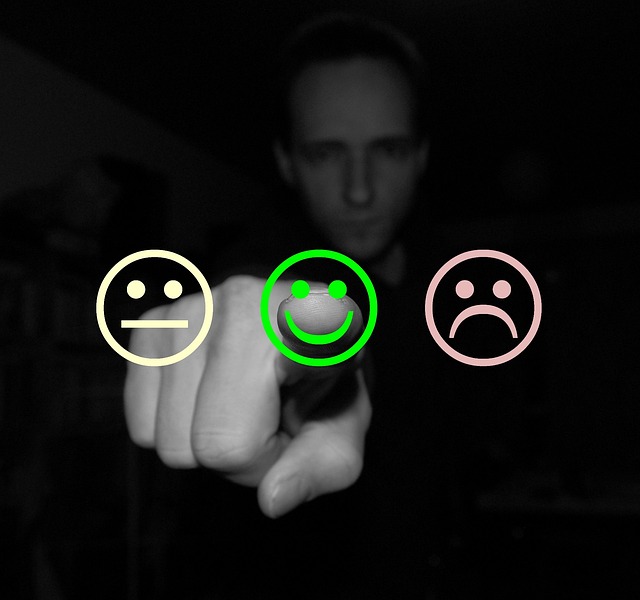 Drei Emojis, ein gelbes neutral, ein grünes Lächelnd und ein rotes Wütend, im Hintergrund ein Mann in schwarz-weiß gehalten zeigt auf den grünen Emoji