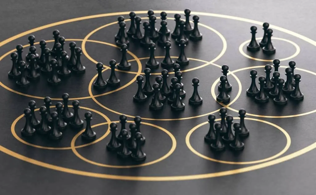 Schwarze Bauern-Schachfiguren innerhalb goldener Kreise auf dunklem Holztisch.