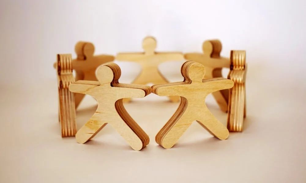 Holzmenschen stehen im Kreis. Weißer Hintergrund. 