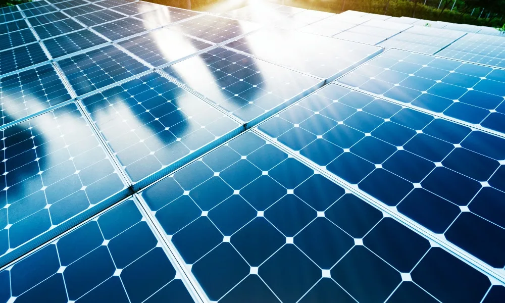 Nahaufnahme von Solarpaneelen. Rand einer grünen Landschaft im oberen Hintergrund.