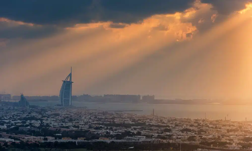 Ausblick auf Dubai mit Meer unter orangem Himmel aus der Ferne.
