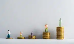 Fünf aufsteigende Münztürme, auf jedem steht eine Menschenfigur. Weißer Hintergrund.